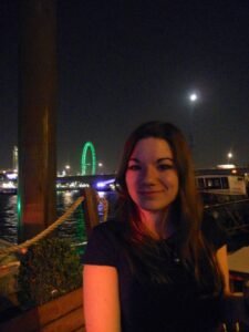 London eye y luna llena en el fondo y chica sonriendo en el primer plano. Es de noche.