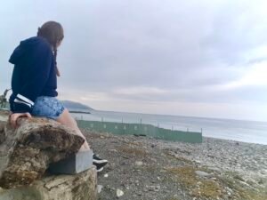 costa de Hualien, Taiwan. chica sentada en un tronco mirando hacia el horizonte