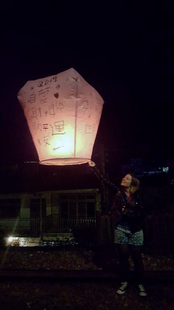 girl following her own path in Taiwan holding a traditional light and letting it go to the night sky