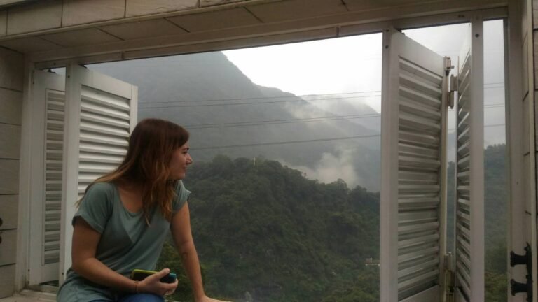 chica mirando por un balcón a un bosque verde